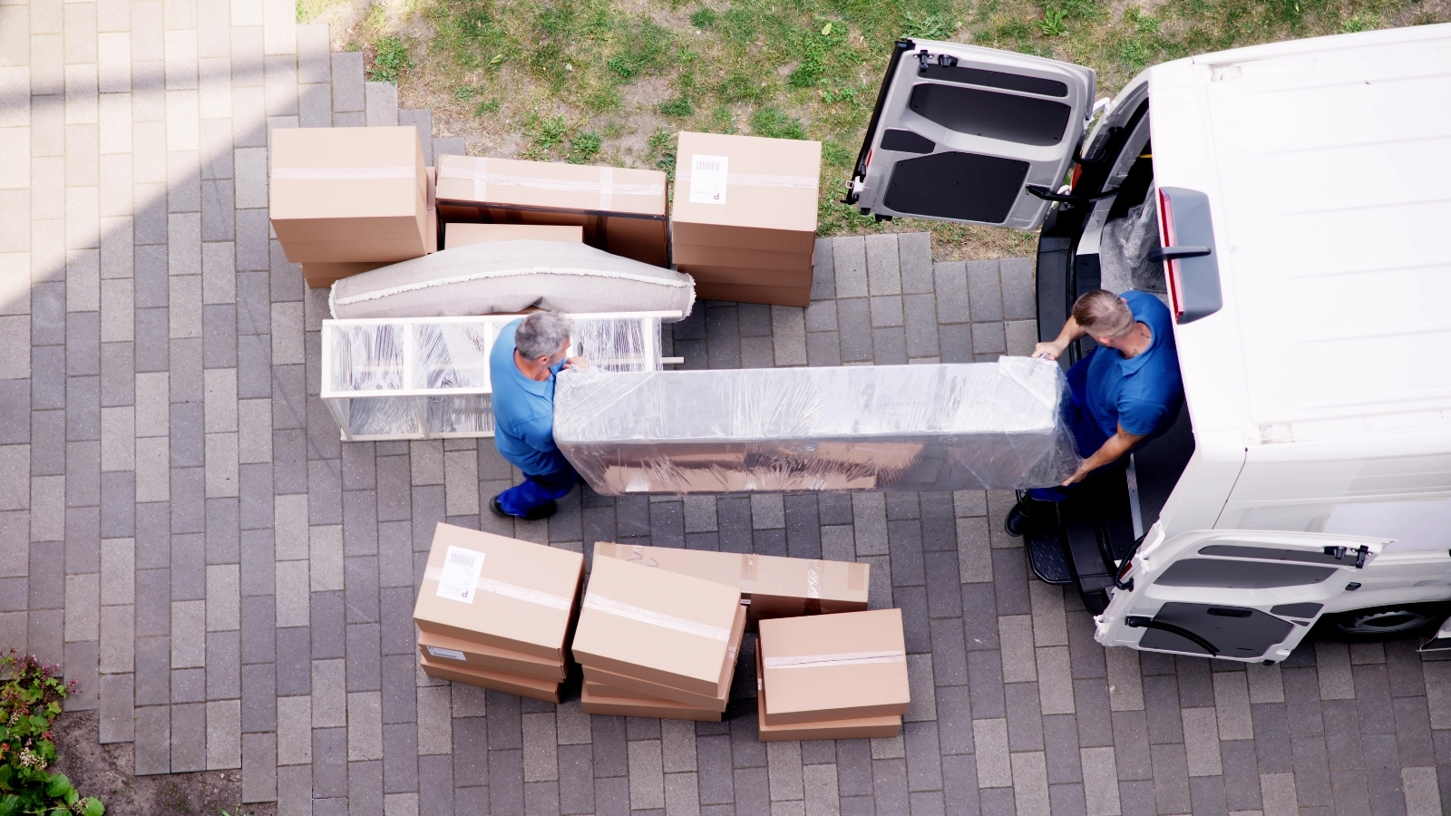 Dos operarios cargando muebles embalados y cajas en una furgoneta de mudanzas