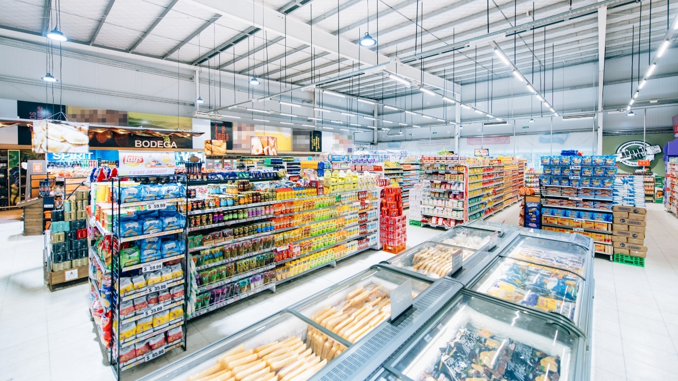 Supermercado amplio con pasillos y vitrinas refrigeradas